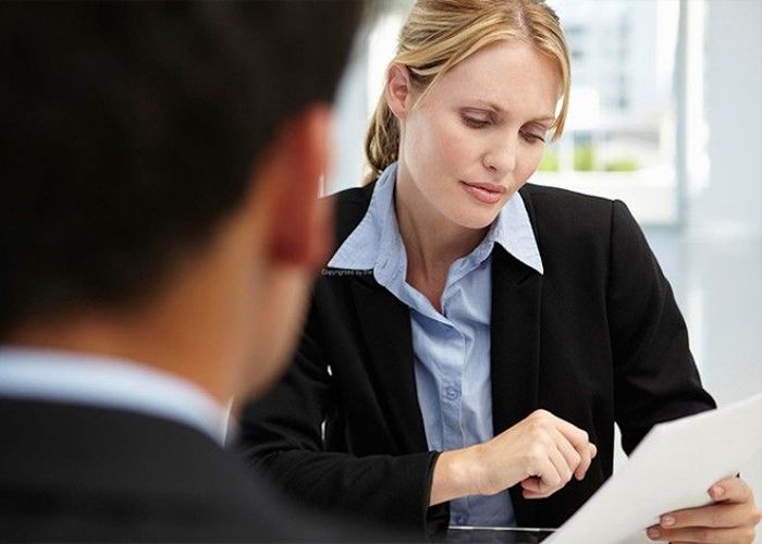 Woman in suite reading a document with a man sat opposite
